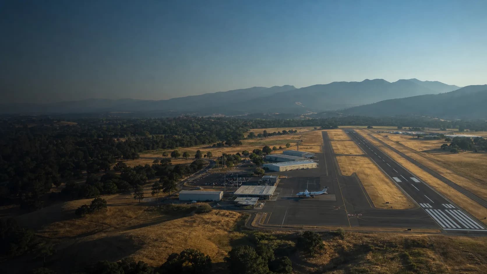 A regional airport runway connecting a community beneath a mountain skyline